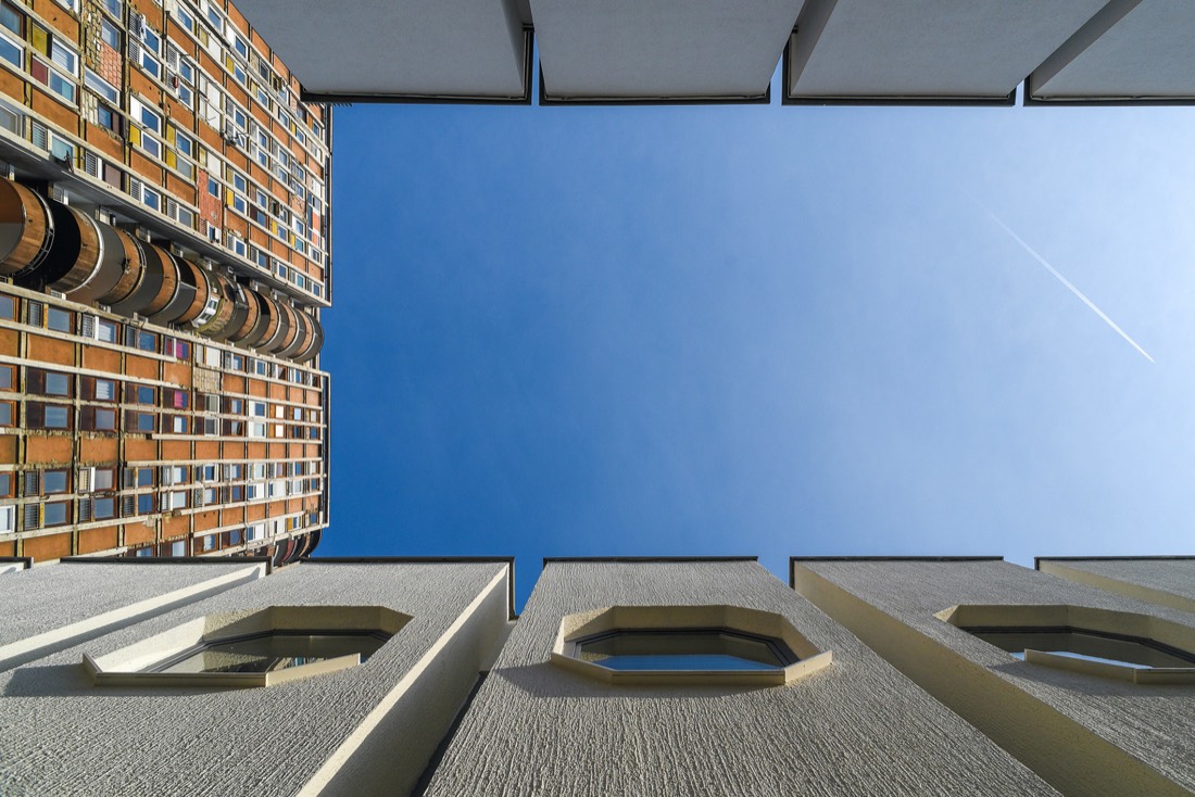 Pogled odozdo na stambenu zgradu brutalističke arhitekture pod plavim nebom