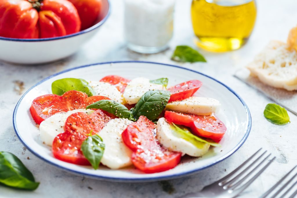 Caprese salata sa paradajzom, mocarelom i bosiljkom na svijetloj pozadini