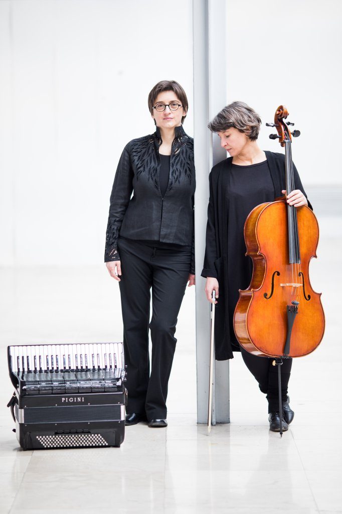 Dvije muzičarke s violončelom i harmonikom u svijetlom enterijeru